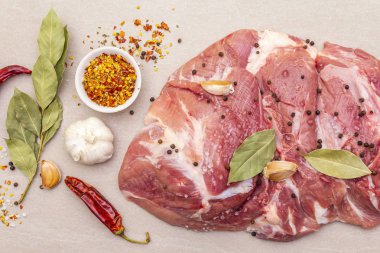 Çiğ domuz omuzu ve baharat. Saha yaprağı, sarımsak. Taştan bir arkaplanda, üst görünümü kapat..