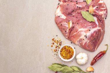 Çiğ domuz omuzu ve baharat. Saha yaprağı, sarımsak. Taştan bir arkaplanda, üst görünümü kapat..