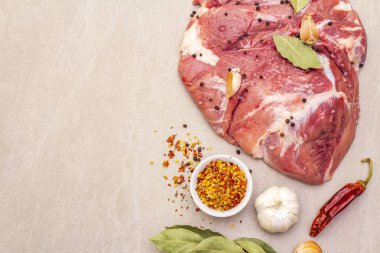 Çiğ domuz omuzu ve baharat. Saha yaprağı, sarımsak. Taştan bir arkaplanda, üst görünümü kapat..