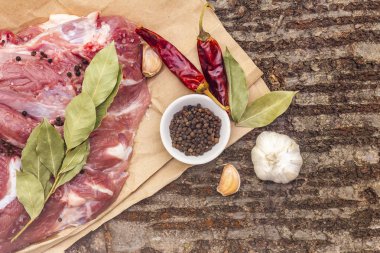 Çiğ domuz omuzu ve baharat. Koyun yaprağı, sarımsak, kırmızı biber. Ahşap kabuk arka planında, kapat, üst görünüm, boşluğu kopyala.