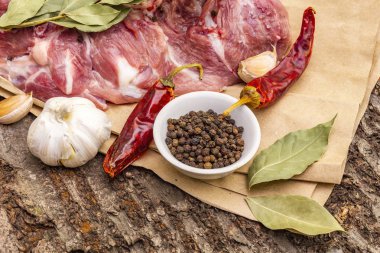 Çiğ domuz omuzu ve baharat. Koyun yaprağı, sarımsak, kırmızı biber. Ahşap bir arka planda, yakın plan.