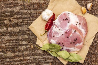 Çiğ domuz omuzu ve baharat. Koyun yaprağı, sarımsak, kırmızı biber. Ahşap kabuk arka planı, üst görünüm, kopyalama alanı.