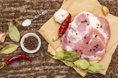 Çiğ domuz omuzu ve baharat. Koyun yaprağı, sarımsak, kırmızı biber. Ahşap bir arka planda, yakın plan, üst manzara.