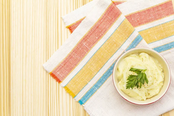 Warm mashed potatoes in a ceramic bowl with fresh parsley. On a vintage linen napkin on a stone background, copy space, top view, close up. — Stock Photo, Image