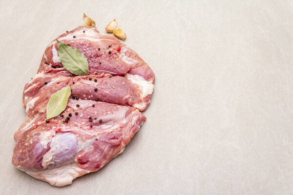 Сырое свиное плечо со специями. Лист лавровый, чеснок. На каменном фоне, копировальное пространство
.