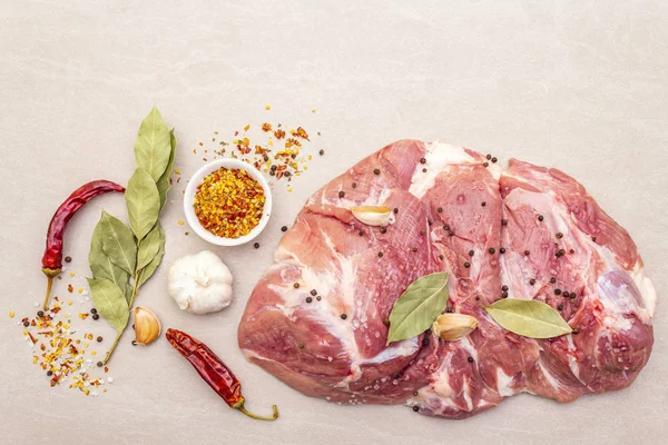 Çiğ domuz omuzu ve baharat. Saha yaprağı, sarımsak. Taştan bir arkaplanda, üst görünümü kapat..