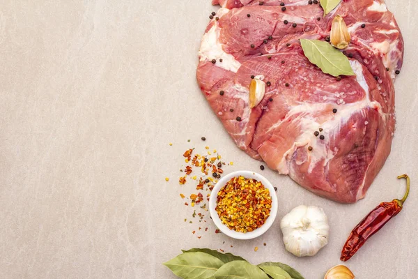 Çiğ domuz omuzu ve baharat. Saha yaprağı, sarımsak. Taştan bir arkaplanda, üst görünümü kapat..