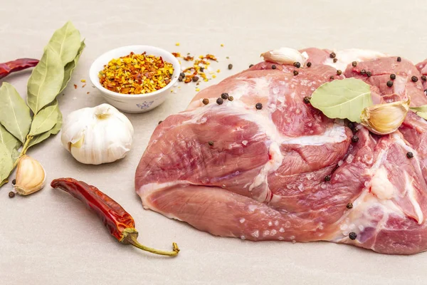 Raw pork shoulder with spices. Bay leaf, garlic. On a stone background, close up.