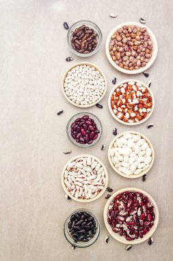 Assortment of beans on a stone background. Crimson cranberry, red, painted pony, black turtle, brown, black-eyed, Jacob's Cattle (heirloom) and lima, top view. clipart