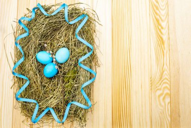 Söğüt ağacı fokları ve ahşap masa arkasındaki mavi benekli kurdeleli samanlıkta paskalya yumurtası kavramı.