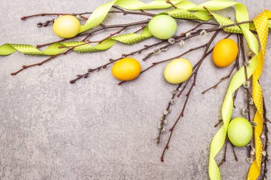 Paskalya yumurtası kavramı söğüt ağacı dallarını benekli saten kurdelelerle kaplar. Bir taş arkaplanda, boşluk kopyala, üst görünüm.