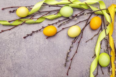 Paskalya yumurtası kavramı söğüt ağacı dallarını benekli saten kurdelelerle kaplar. Bir taş arkaplanda, boşluk kopyala, üst görünüm.