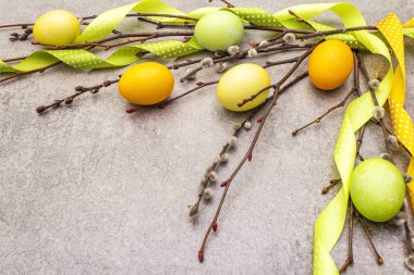 Paskalya yumurtası kavramı söğüt ağacı dallarını benekli saten kurdelelerle kaplar. Taş bir arkaplanda, boşluğu kopyala.