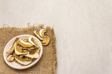 Kurutulmuş mantar boletus edulis (bozuk para çöreği, cep, porcino). Vejetaryen yemeği (vejetaryen yemeği) içerir. Taş zeminde çuval bezli seramik bir kasede, boşluğu kopyala.