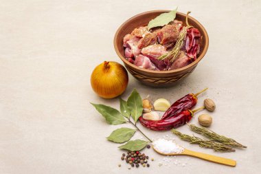Çiğ domuz omzu. Baharatlar, kuru otlar, sarımsak, biberiye, defne yaprağı, acı biber, hindistan cevizi, biber, soğan, tuz. Salamura et için gerekli malzemeler. Taştan arka planda kırsal seramik kasede.
