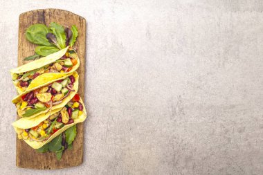 Tavuk etli Meksika tacosu, kırmızı fasulye, tahta tahtada taze sebzeler. Latin Amerika yemekleri, taş arka plan, üst görünüm kopyalama alanı.