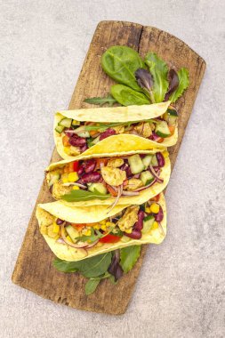 Tavuk etli Meksika tacosu, kırmızı fasulye, tahta tahtada taze sebzeler. Latin Amerika yemekleri, taş arka plan, üst görünüm kopyalama alanı.