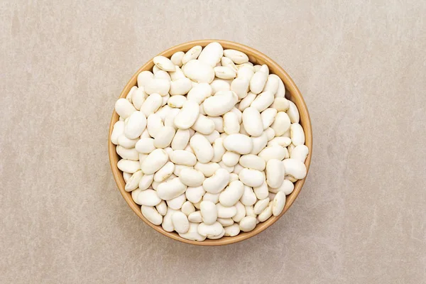 Dry lima beans in ceramic bowl on stone background, top view, wallpaper, close up. — Stock Photo, Image