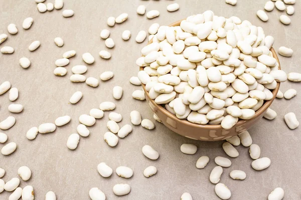 Dry lima beans in ceramic bowl on stone background, top view, wallpaper, close up. — Stock Photo, Image