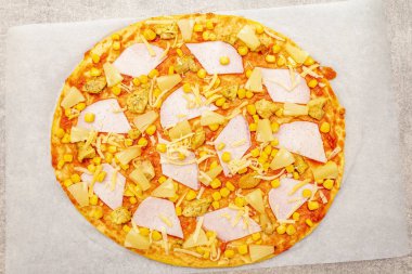 Taş zemin üzerinde parşömen üzerinde çiğ Hawai pizzası..