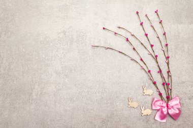 Suni dekoratif söğüt dalları ve tahta tavşan figürleri. Paskalya kartları, duvar kağıtları, taştan arka plan. Üst görünüm, alanı kopyala.