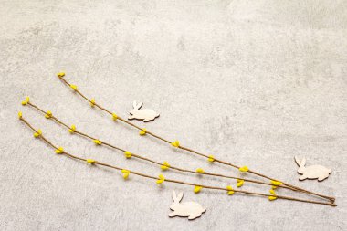 Suni dekoratif söğüt dalları ve tahta tavşan figürleri. Paskalya kartları, duvar kağıtları, taştan arka plan. Boşluğu kopyala.