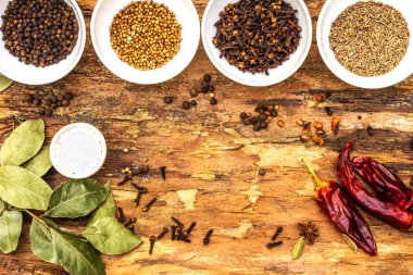 Farklı baharat ve otlar. Karabiber, baharat, kimyon, acı biber, defne yaprağı, kişniş, tuz. Ahşap kabuk arka plan, üst görünüm.
