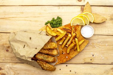 Tahta üzerinde balık ve patates kızartması. Masadaki parşömen kağıdında. Geleneksel İngiliz yemekleri..
