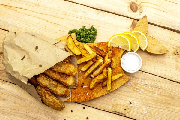 식탁 위에 양피지로 된 나무 위에 생선 과 감자칩을 올려 놓았습니다. 전통적 인 영국 음식, 맨 위 사진. — 스톡 사진