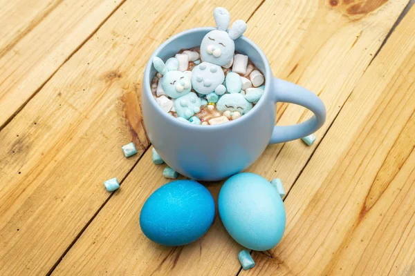 Wielkanocne dzieci gorąca czekolada lub kakao z zabawnymi królikami piankowymi i pisankami. Na drewnianym tle, zbliżenie — Zdjęcie stockowe