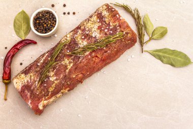 Çiğ domuz filetosu, türler ve bitkiler. Taş bir arka planda büyük bir parça salamura et (marine edilmiş), üst manzara, kapat