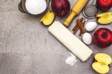 Elmalı turta malzemeleri pişirme konsepti. Tarçınlı taze elmalar, un, şeker, yumurta. Taş zemin üzerinde aşçılık süreci, üst görünüm