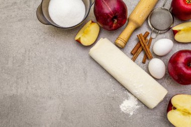 Elmalı turta malzemeleri pişirme konsepti. Tarçınlı taze elmalar, un, şeker, yumurta. Taş zemin üzerinde aşçılık süreci, üst görünüm