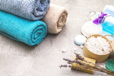 Spa seti, doğal malzemeler. Banyo havluları, lavantalı deniz tuzu, doğal zeytin sabunu, duş jeli, krema ve fırça. Taş bir arka planda
