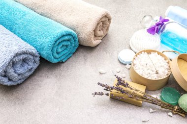 Spa seti, doğal malzemeler. Banyo havluları, lavantalı deniz tuzu, doğal zeytin sabunu, duş jeli, krema ve fırça. Taş bir arka planda