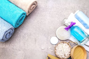 Spa seti, doğal malzemeler. Banyo havluları, lavantalı deniz tuzu, doğal zeytin sabunu, duş jeli, krema ve fırça. Taş bir arkaplanda, üst görünüm
