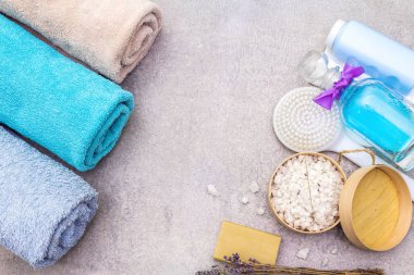Spa konsepti, doğal malzemeler. Banyo havluları, lavantalı deniz tuzu doğal zeytin sabunu, duş jeli, fırça. Taş bir arkaplanda, üst görünüm