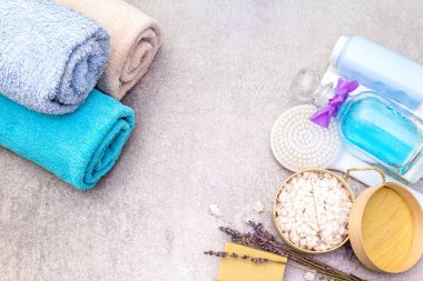 Spa konsepti, doğal malzemeler. Banyo havluları, lavantalı deniz tuzu doğal zeytin sabunu, duş jeli, fırça. Taş bir arkaplanda, üst görünüm