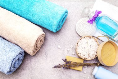 Spa konsepti, doğal malzemeler. Banyo havluları, lavantalı deniz tuzu doğal zeytin sabunu, duş jeli, fırça. Taş bir arkaplanda, üst görünüm