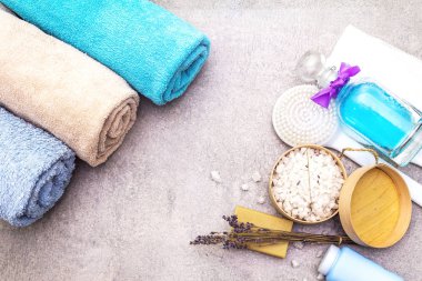 Spa konsepti, doğal malzemeler. Banyo havluları, lavantalı deniz tuzu doğal zeytin sabunu, duş jeli, fırça. Taş bir arkaplanda, üst görünüm