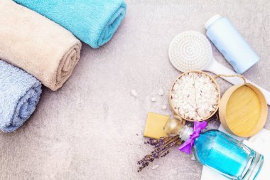 Spa konsepti, doğal malzemeler. Banyo havluları, lavantalı deniz tuzu doğal zeytin sabunu, duş jeli, fırça. Taş bir arkaplanda, üst görünüm