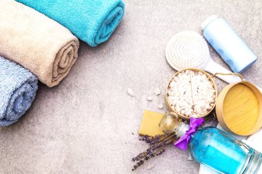 Spa konsepti, doğal malzemeler. Banyo havluları, lavantalı deniz tuzu doğal zeytin sabunu, duş jeli, fırça. Taş bir arkaplanda, üst görünüm