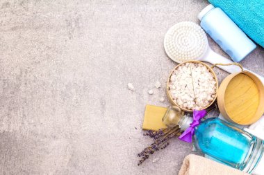 Spa konsepti, doğal malzemeler. Banyo havluları, lavantalı deniz tuzu doğal zeytin sabunu, duş jeli, fırça. Taş bir arkaplanda, üst görünüm
