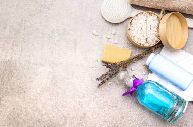 Spa konsepti, doğal malzemeler. Banyo havluları, lavantalı deniz tuzu doğal zeytin sabunu, duş jeli, fırça. Taş bir arkaplanda, üst görünüm