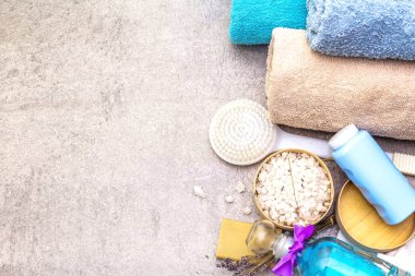 Spa konsepti, doğal malzemeler. Banyo havluları, lavantalı deniz tuzu doğal zeytin sabunu, duş jeli, fırça. Taş bir arkaplanda, üst görünüm