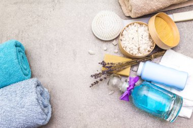 Spa konsepti, doğal malzemeler. Banyo havluları, lavantalı deniz tuzu doğal zeytin sabunu, duş jeli, fırça. Taş bir arkaplanda, üst görünüm