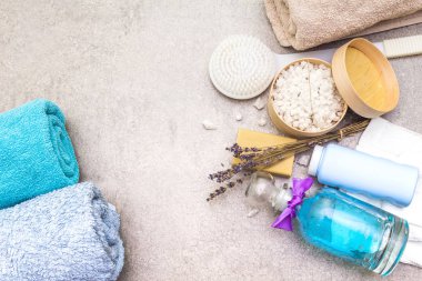 Spa konsepti, doğal malzemeler. Banyo havluları, lavantalı deniz tuzu doğal zeytin sabunu, duş jeli, fırça. Taş bir arkaplanda, üst görünüm