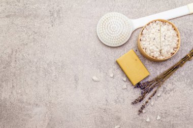 Spa konsepti, doğal malzemeler. Lavantalı deniz tuzu, doğal zeytin sabunu ve fırça. Taş bir arkaplanda, üst görünüm