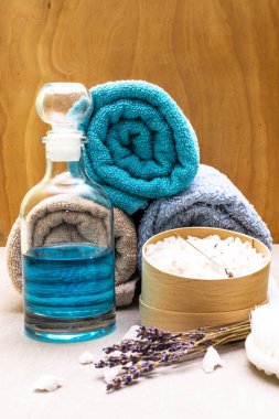 Spa konsepti, doğal malzemeler. Banyo havluları, lavantalı deniz tuzu, duş jeli, fırça. Bir taş ve ahşap arka planda