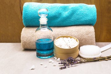 Spa konsepti, doğal malzemeler. Banyo havluları, lavantalı deniz tuzu, duş jeli, fırça. Bir taş ve ahşap arka planda
